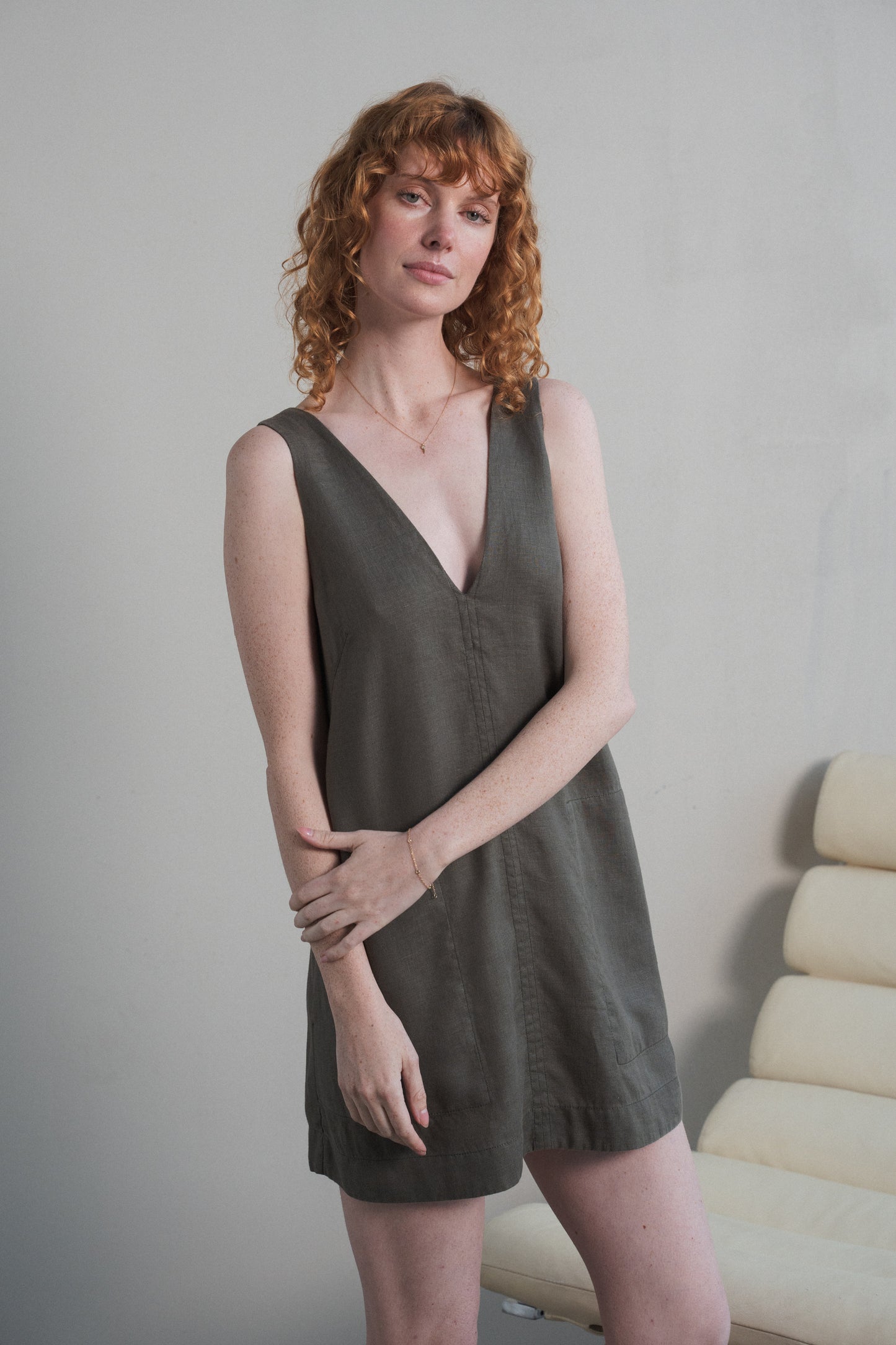 LILLY PILLY w woman standing on a beach wearing a Isla linen dress in Khaki with a neutral background