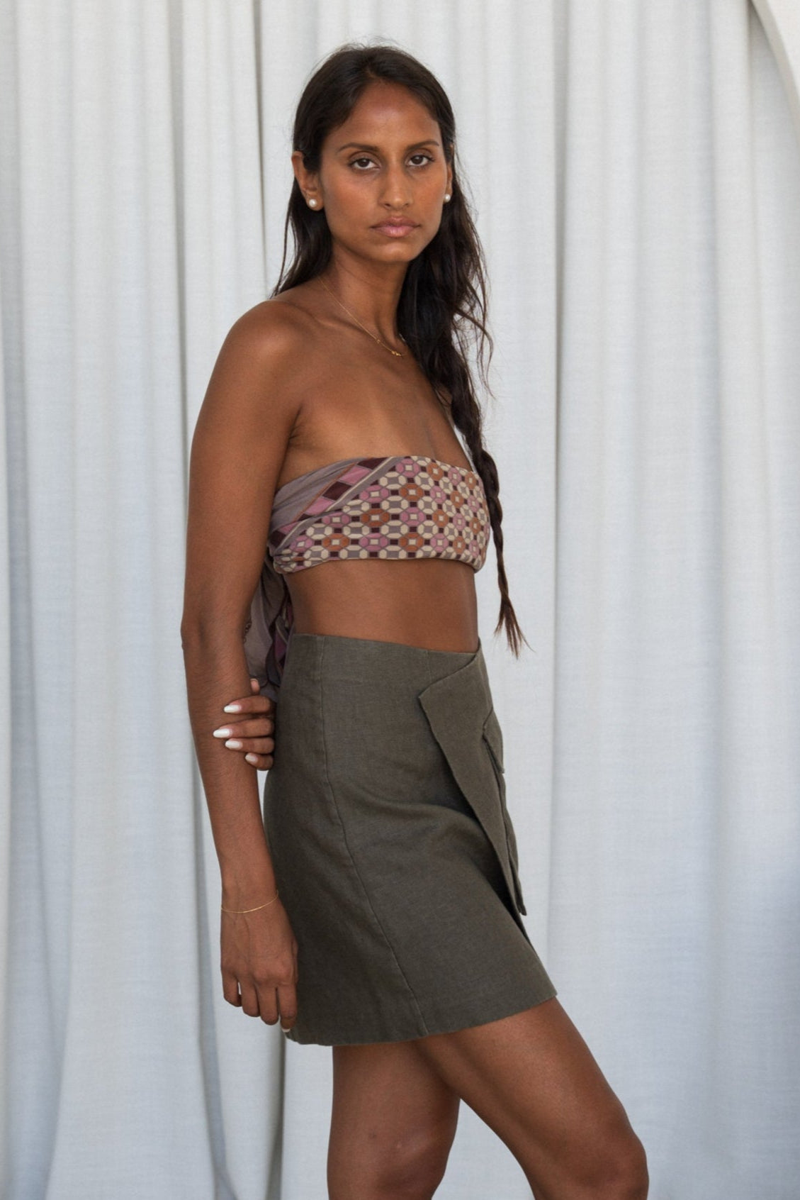 Woman wearing a patterned top and khaki Betty linen against a white curtain background