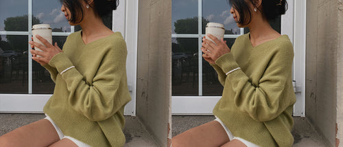 LILLY PILLY woman in an a olive green, June Cashmere knit, sweater holding a coffee cup in front of a glass door.