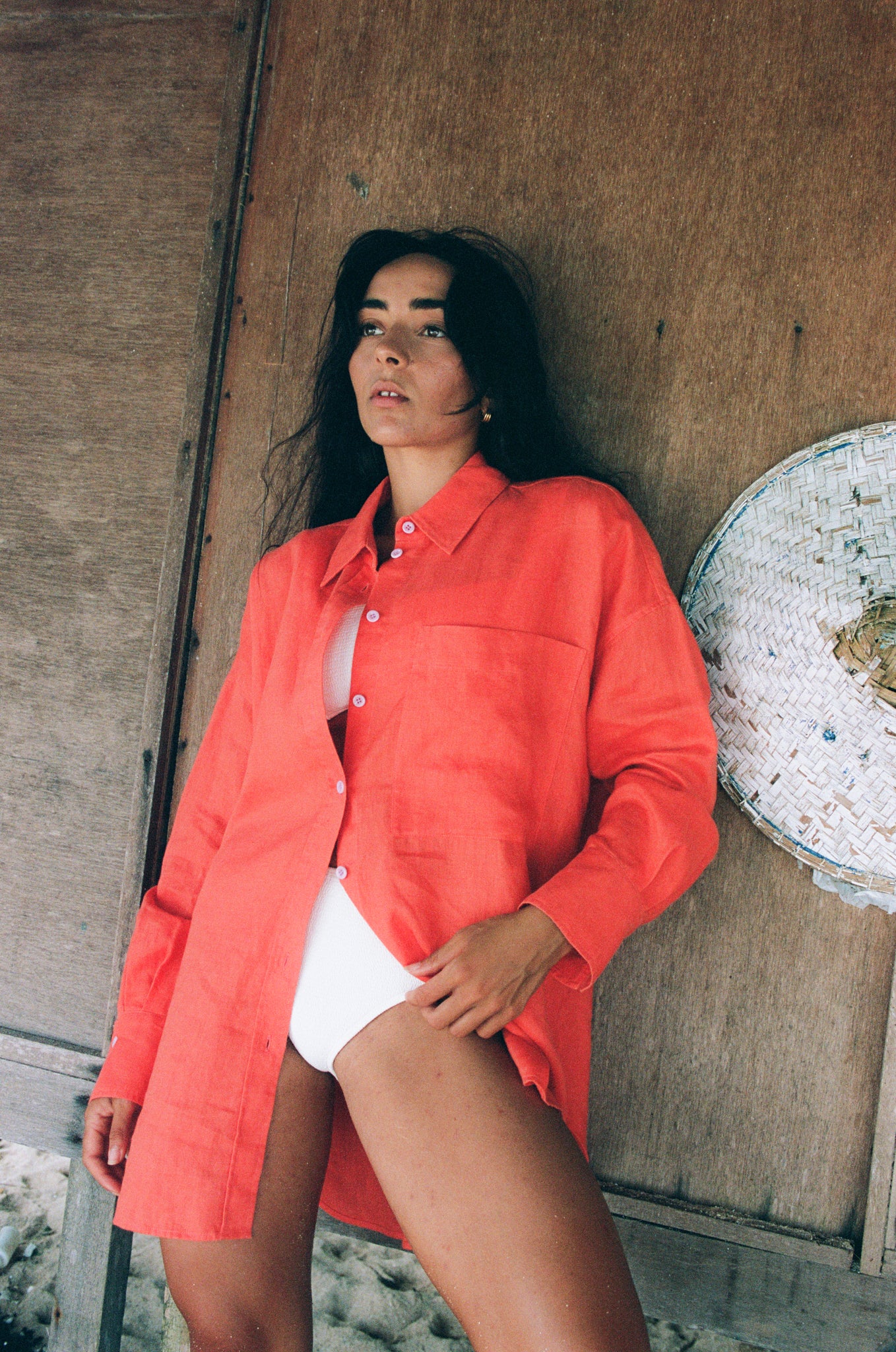 LILLY PILLY woman wearing a spritz Kirra linen shirt leaning against a wooden wall.
