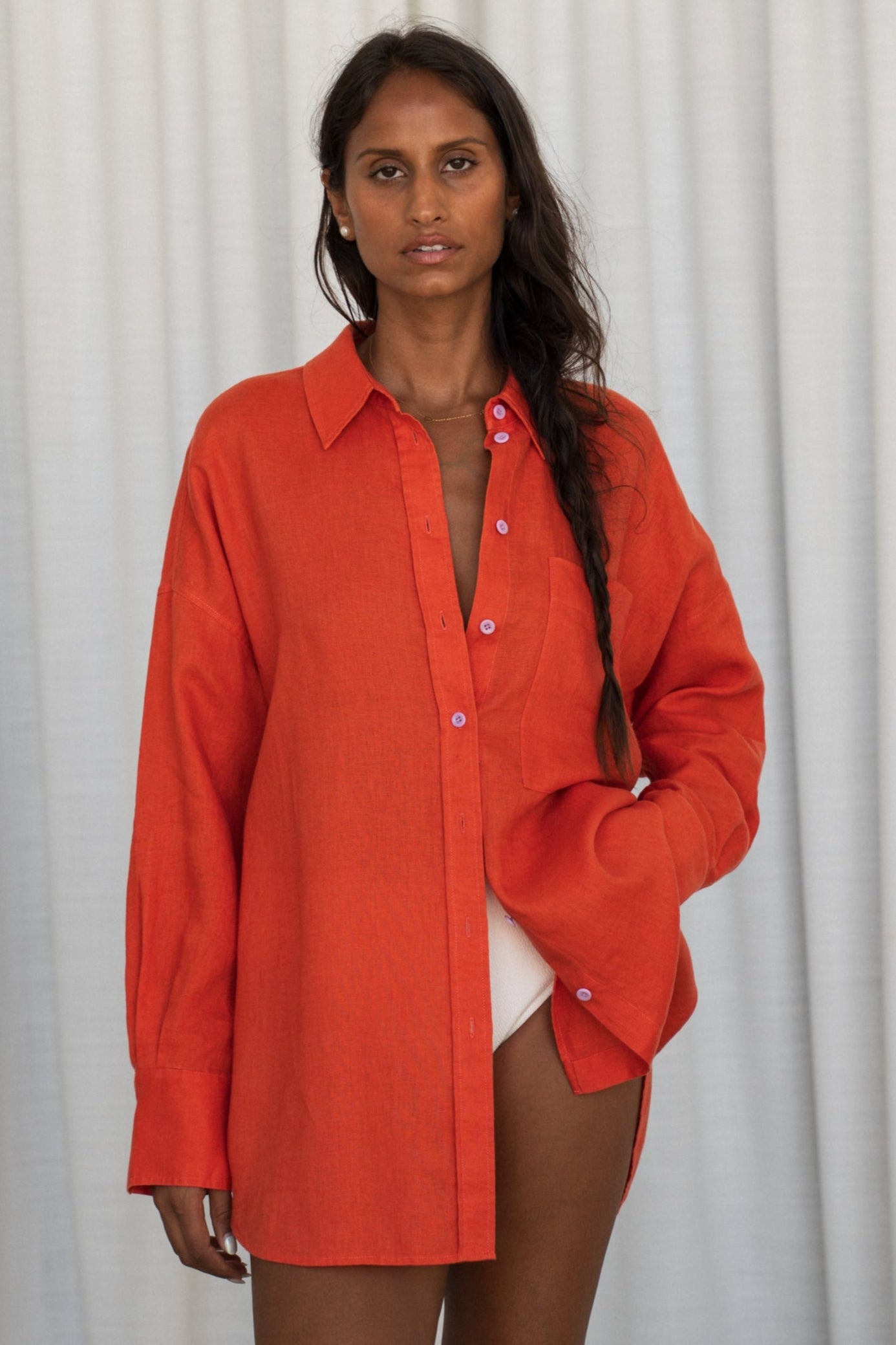 LILLY PILLY woman wearing a spritz Kirra linen shirt leaning against a plain background